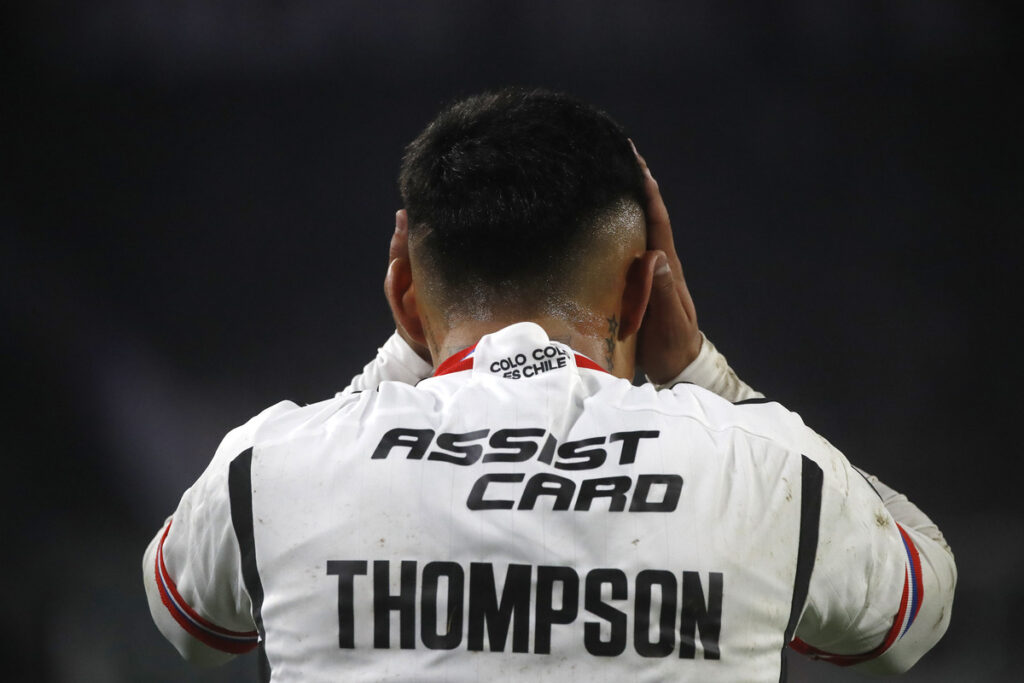 Jordhy Thompson de espaldas a la cámara se toma la cabeza en medio de un partido de Colo-Colo,