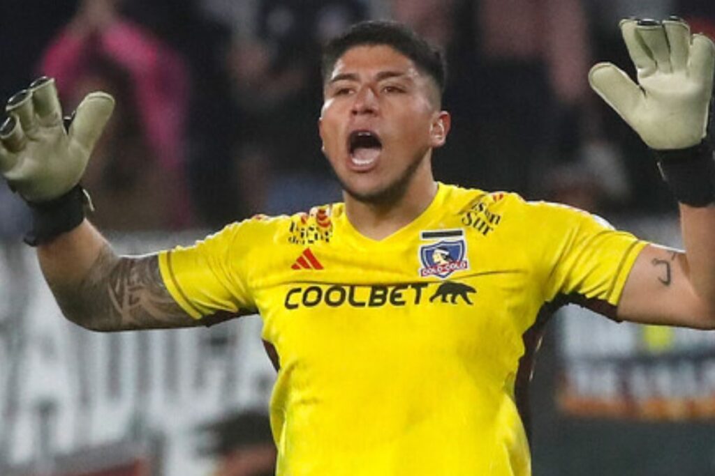 Brayan Cortés con la camiseta de Colo-Colo, con la boca abierta y los brazos levantados