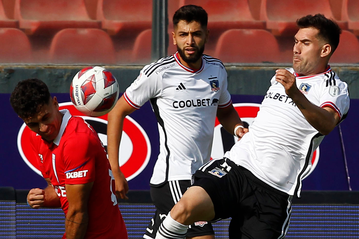 César Fuentes e Ignacio Saavedra disputando un balón ante la atenta mirada de Jeyson Rojas, todo esto en medio de un partido de Colo-Colo y Universidad Católica por el Campeonato Nacional 2023.