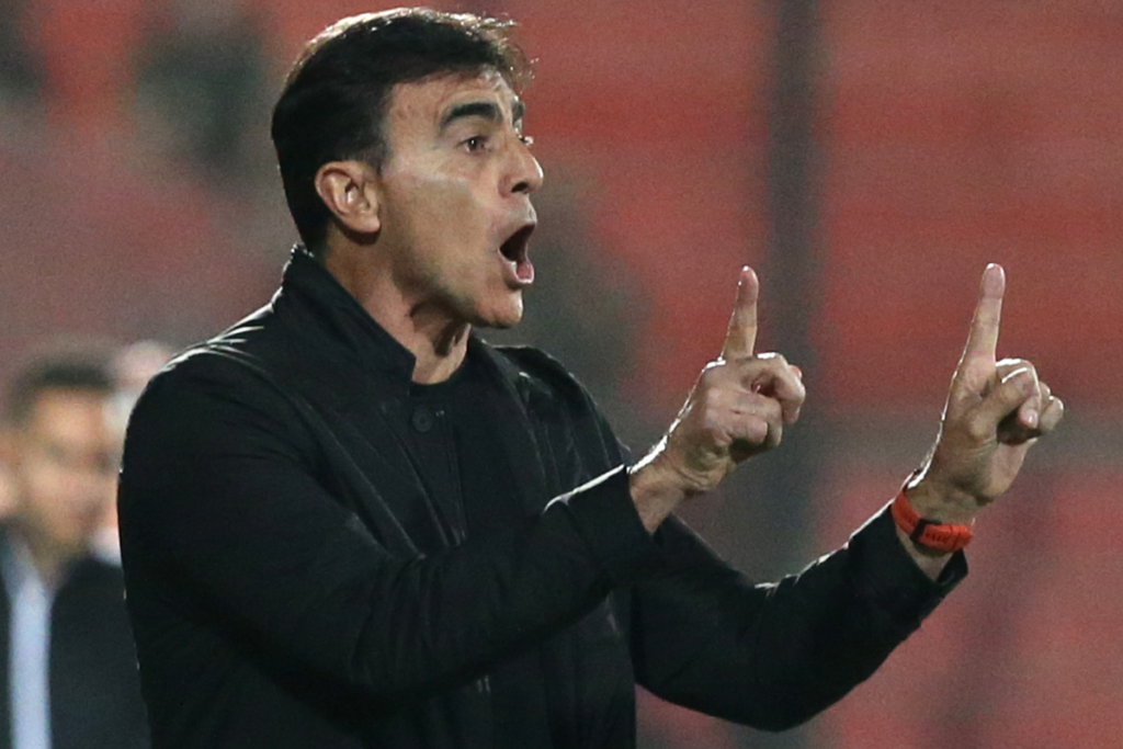 Gustavo Quinteros repartiendo instrucciones al borde del terreno de juego en medio de un partido de Colo-Colo ante Unión Española.