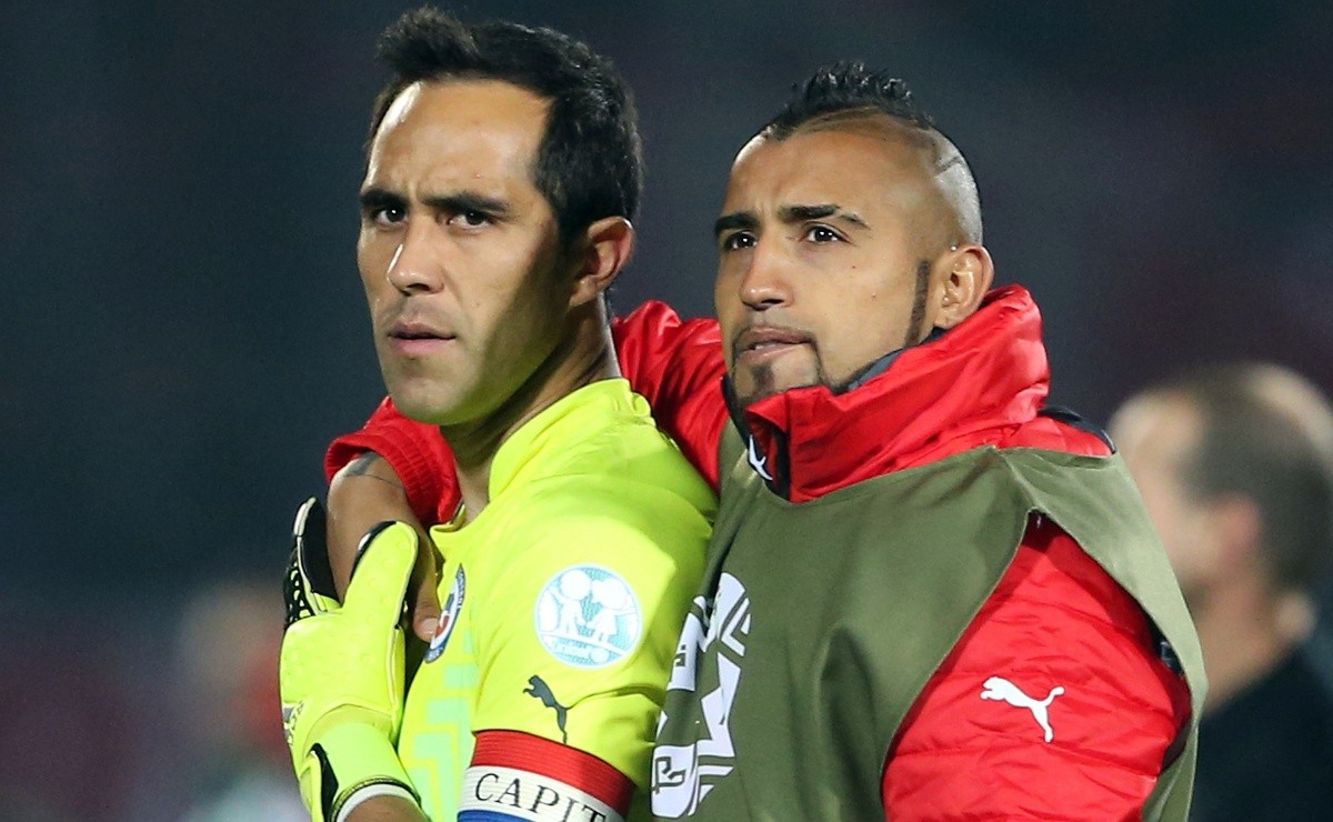 Arturo Vidal abrazando a Claudio Bravo con cara de seriedad.