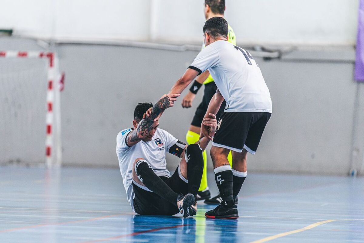 Jugador de Colo-Colo Futsal ayudando a un compañero a ponerse de pié.