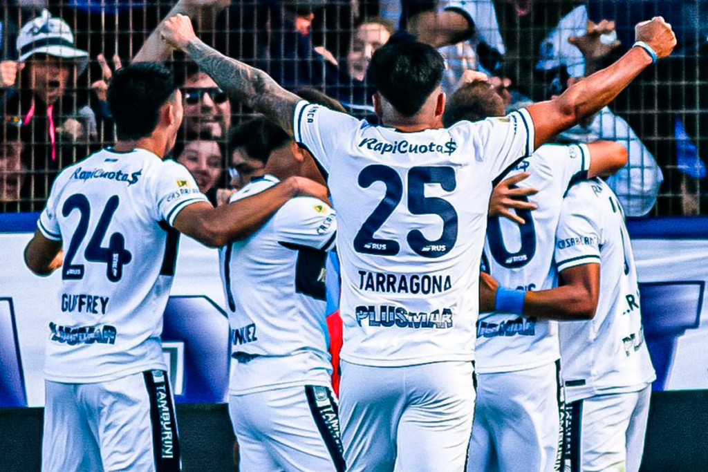 Futbolistas de Gimnasia y Esgrima de la Plata se abrazan y celebran un gol durante la temporada 2023.