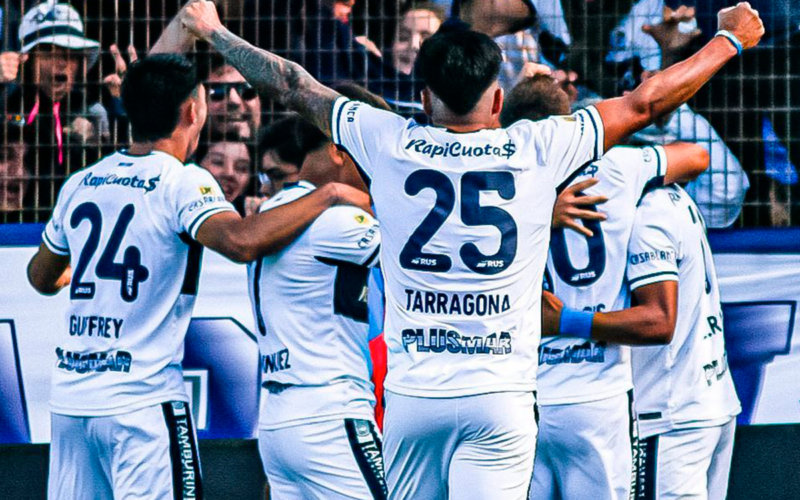 Futbolistas de Gimnasia y Esgrima de la Plata se abrazan y celebran un gol durante la temporada 2023.