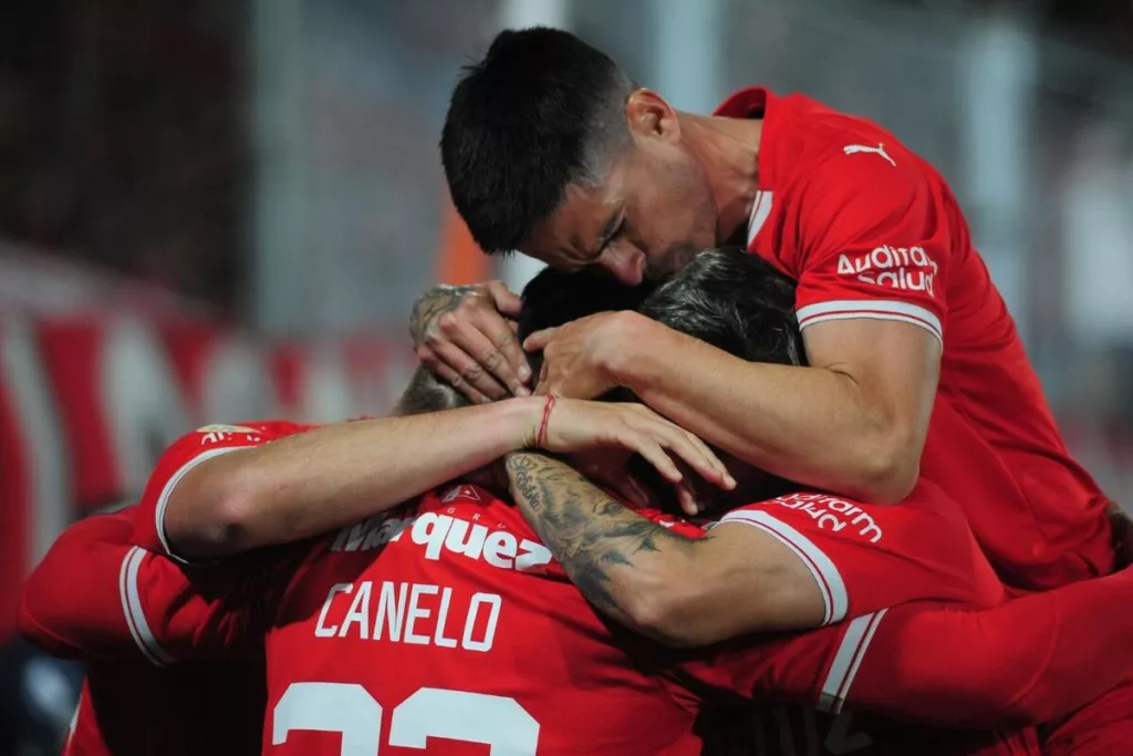 Futbolistas de Independiente de Avellaneda se abrazan y celebran un gol durante la temporada 2023.