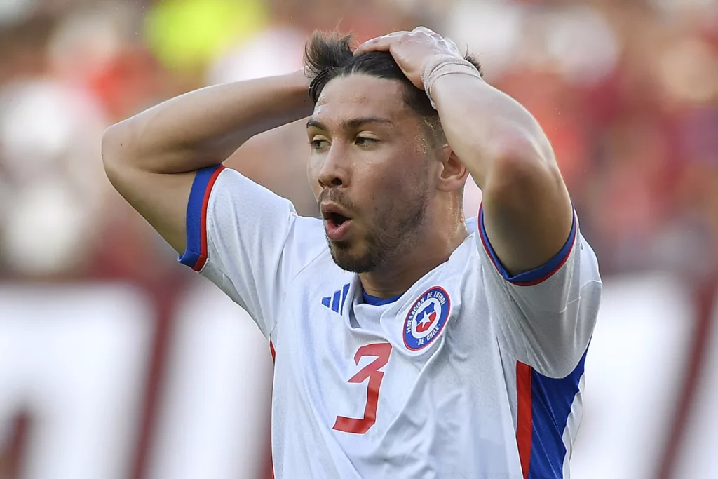 Felipe Loyola agarrándose la cabeza con sus manos mientras disputa un partido por la Selección Chilena.