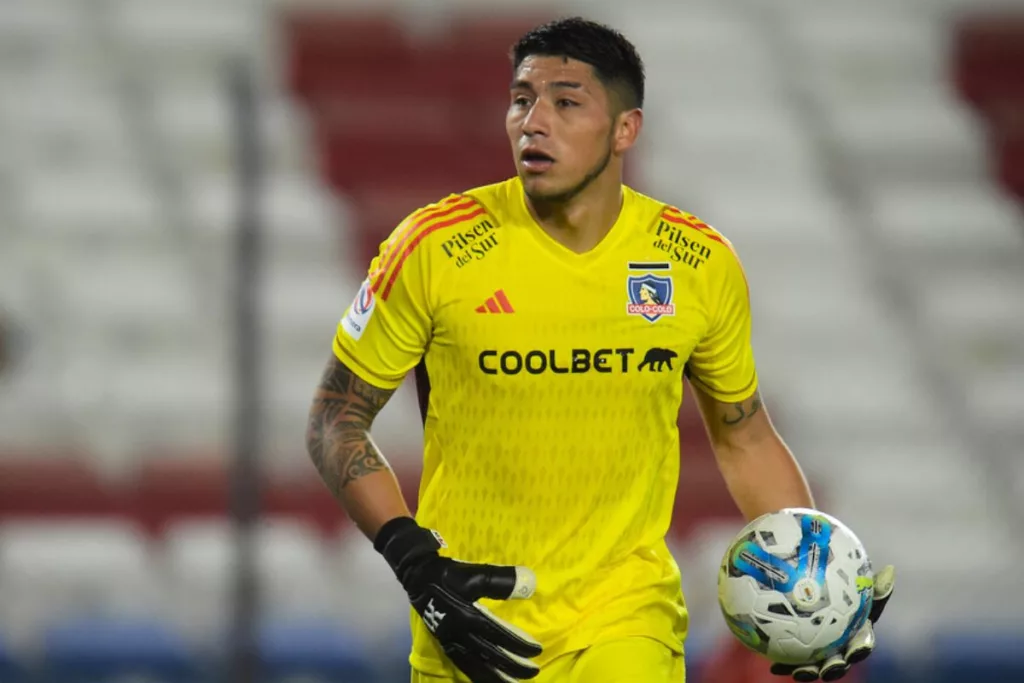 Brayan Cortés con la camiseta amarilla de Colo-Colo y la pelota en su mano.