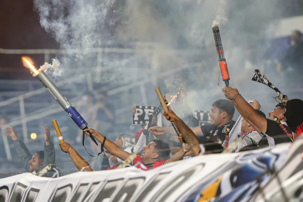 Hinchas de Colo-Colo lanzan fuegos artificiales en pleno encuentro ante Liverpool de Uruguay por el torneo Serie Río de La Plata 2024.