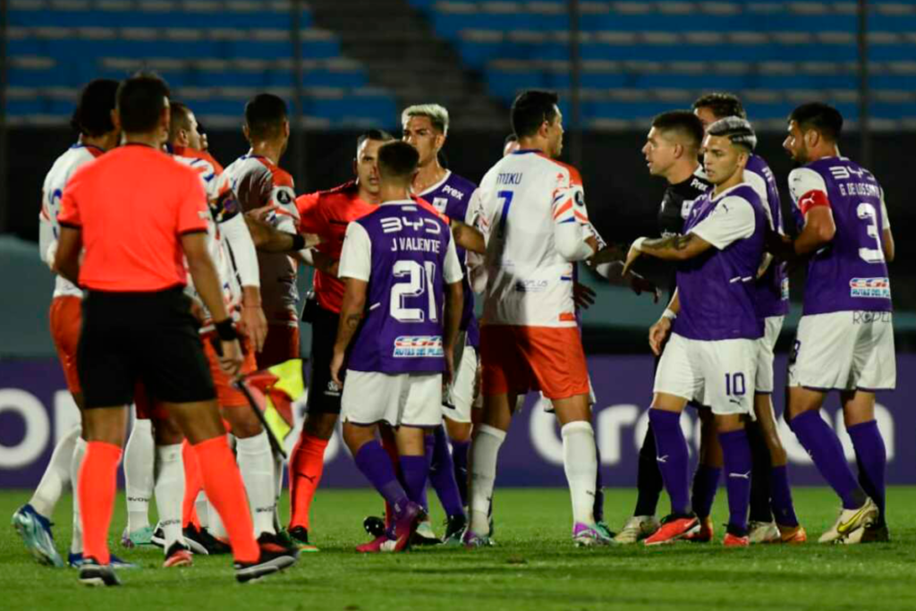 Futbolistas de Puerto Cabello y Defensor Sporting se enfrentan en una discusión junto al cuerpo arbitral durante la Copa Libertadores 2024.