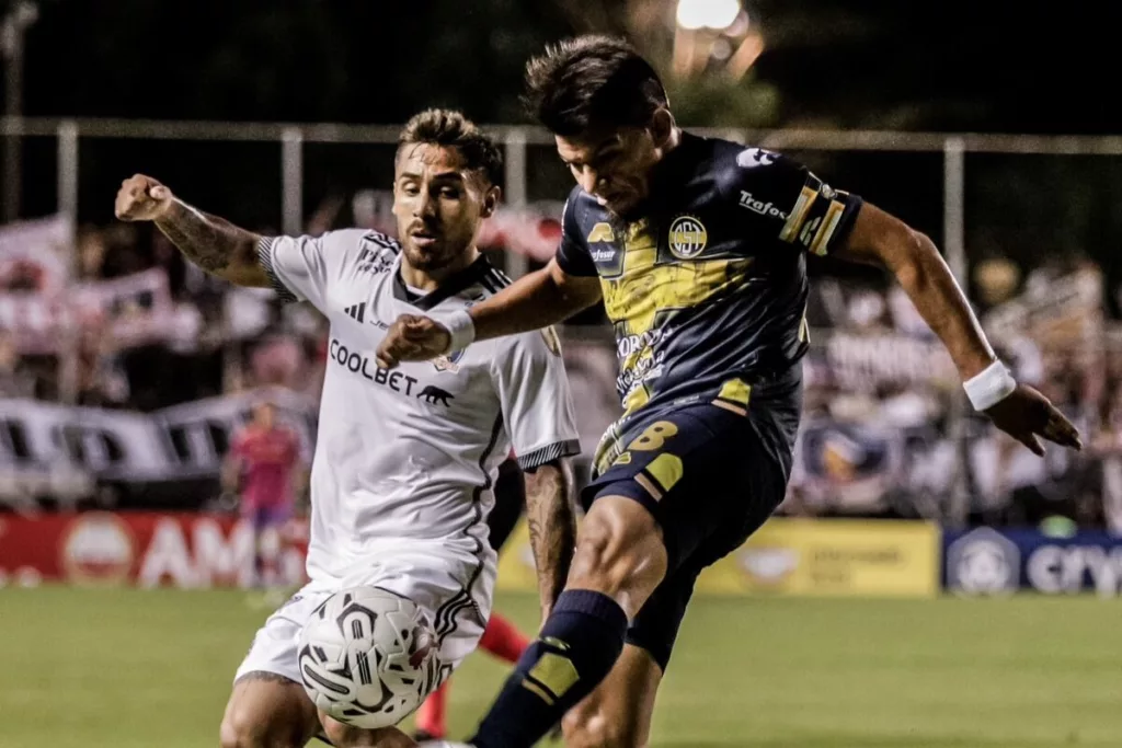 Marcos Bolados disputando un balón con un jugador de Sportivo Trinidense.