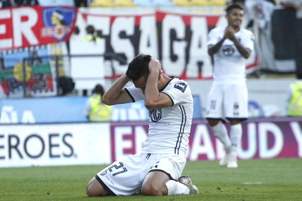 Branco Provoste arrodillado en el piso se toma su cabeza y se lamenta en pleno partido con la camiseta de Colo-Colo durante la temporada 2020.