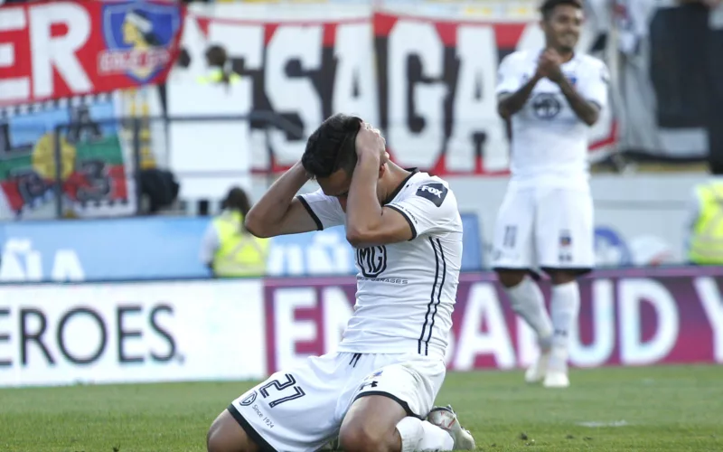 Branco Provoste arrodillado en el piso se toma su cabeza y se lamenta en pleno partido con la camiseta de Colo-Colo durante la temporada 2020.