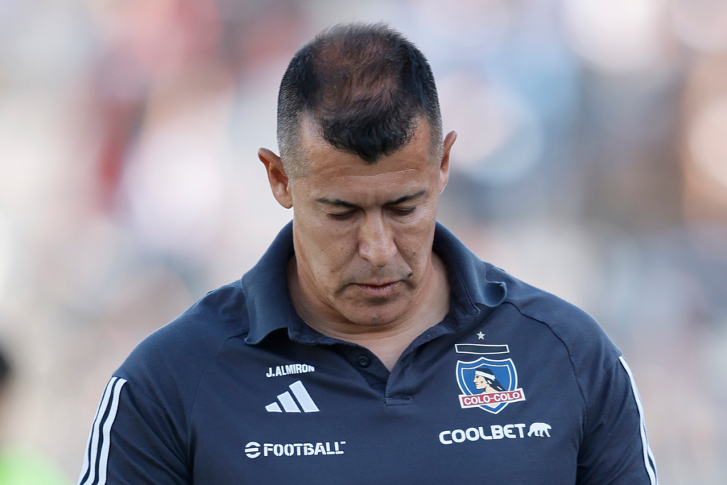 Jorge Almirón con cara triste y la mirada cabizbaja en pleno partido dirigiendo a Colo-Colo durante la temporada 2024.