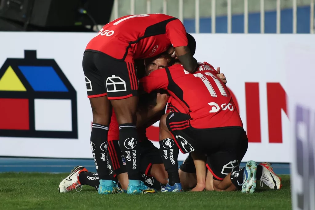 Futbolistas de Colo-Colo se abrazan y celebran un gol a finales de la temporada 2023.