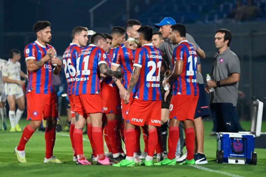 Futbolistas de Cerro Porteño se reúnen al borde del terreno de juego para recibir una instrucción de su director técnico.