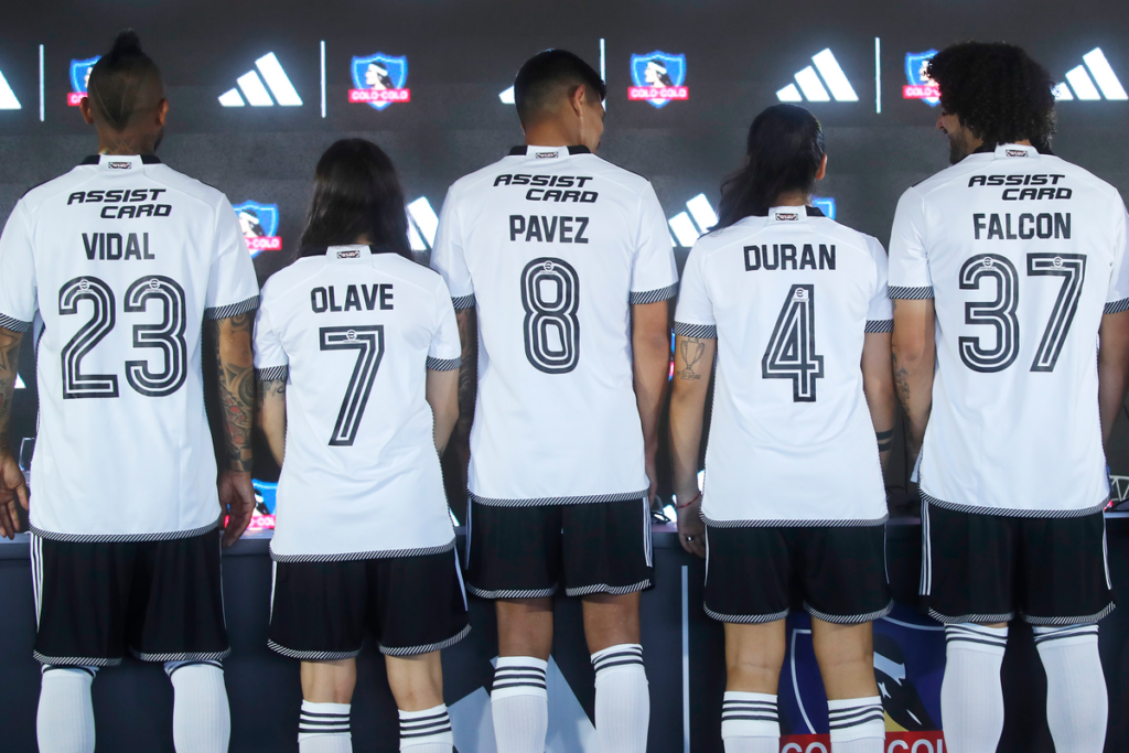 Futbolistas del plantel femenino y masculino de Colo-Colo muestran de espaldas la camiseta de la temporada 2024.