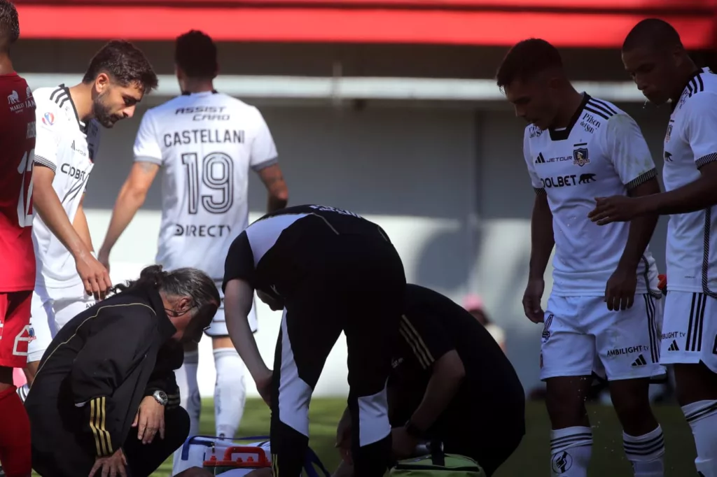 Jugadores de Colo-Colo mientras atendían a un futbolista en el campo de juego.