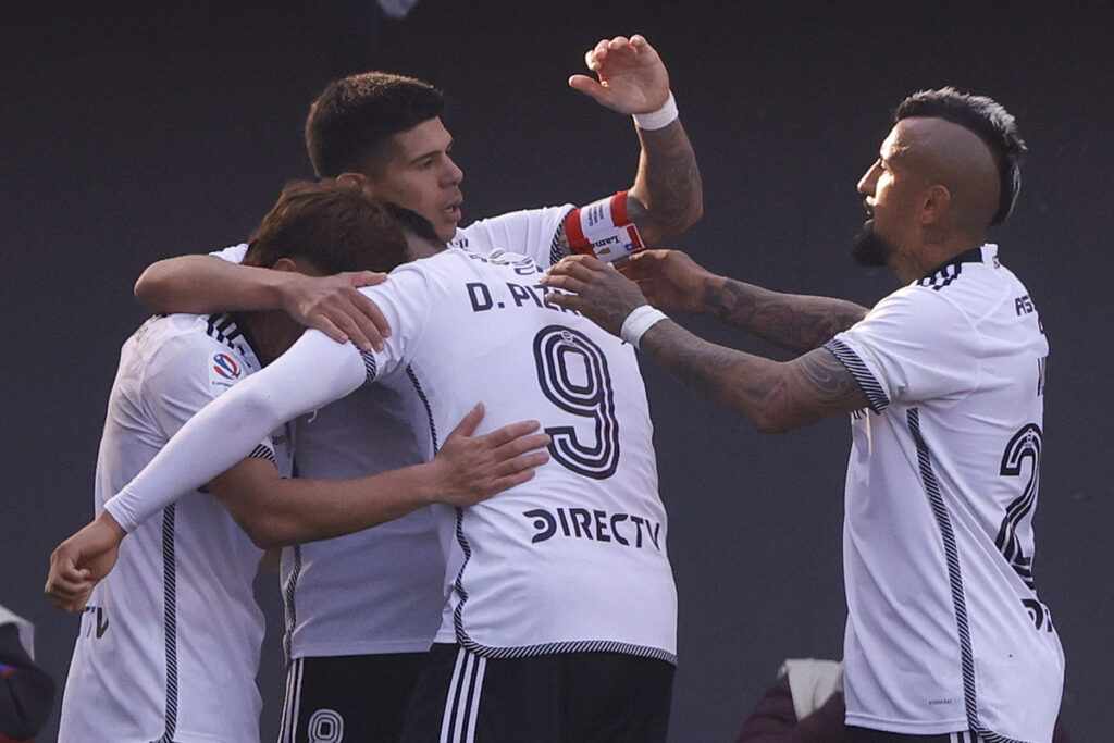 Jugadores de Colo-Colo abrazados celebrando un gol.