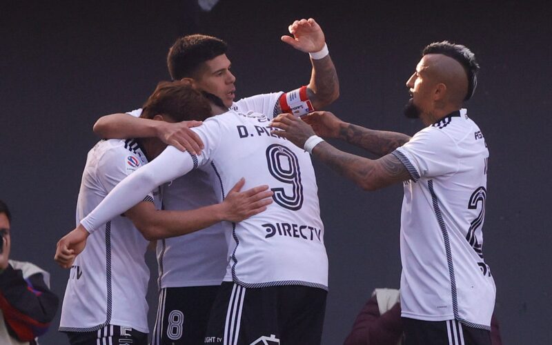 Jugadores de Colo-Colo celebrando abrazados un gol contra Audax Italiano.