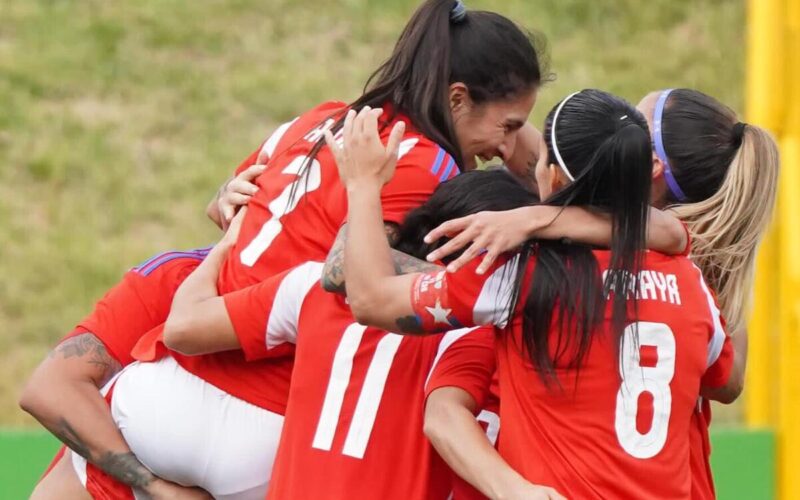 Jugadoras de La Roja femenina abrazadas celebrando un gol.