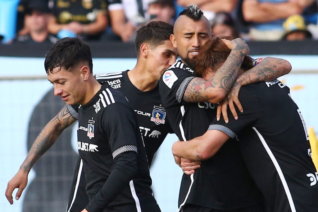 Jugadores de Colo-Colo abrazados celebrando un gol.