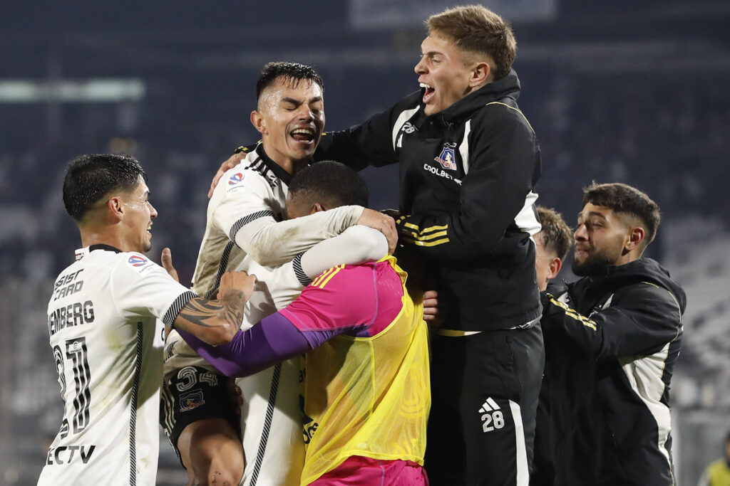 Jugadores de Colo-Colo abrazados celebrando un gol.