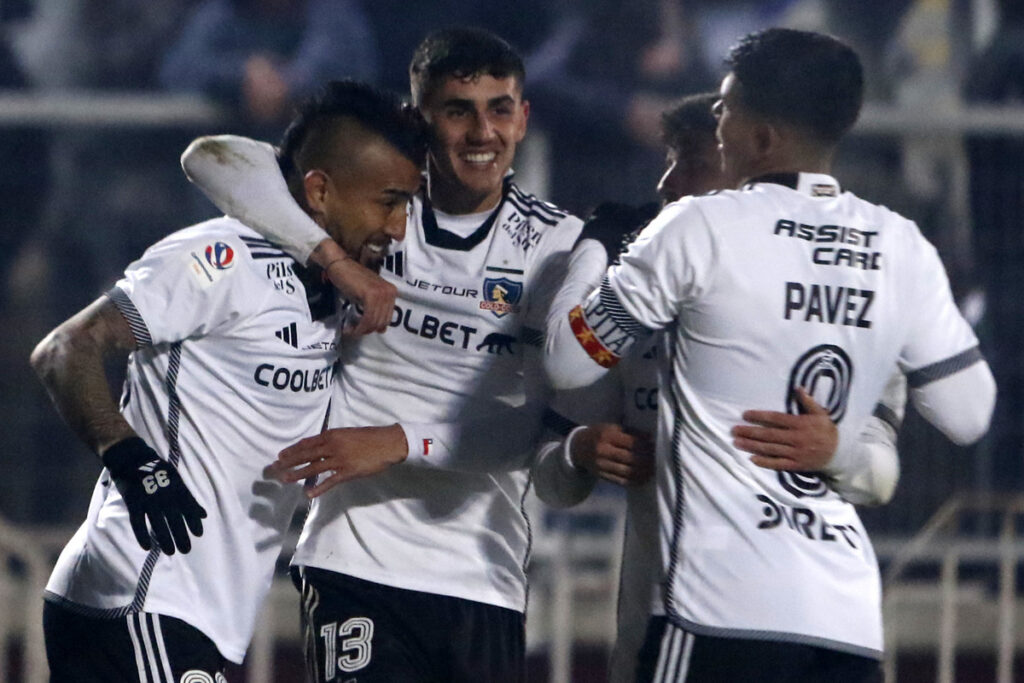 Jugadores de Colo-Colo abrazados celebrando un gol.