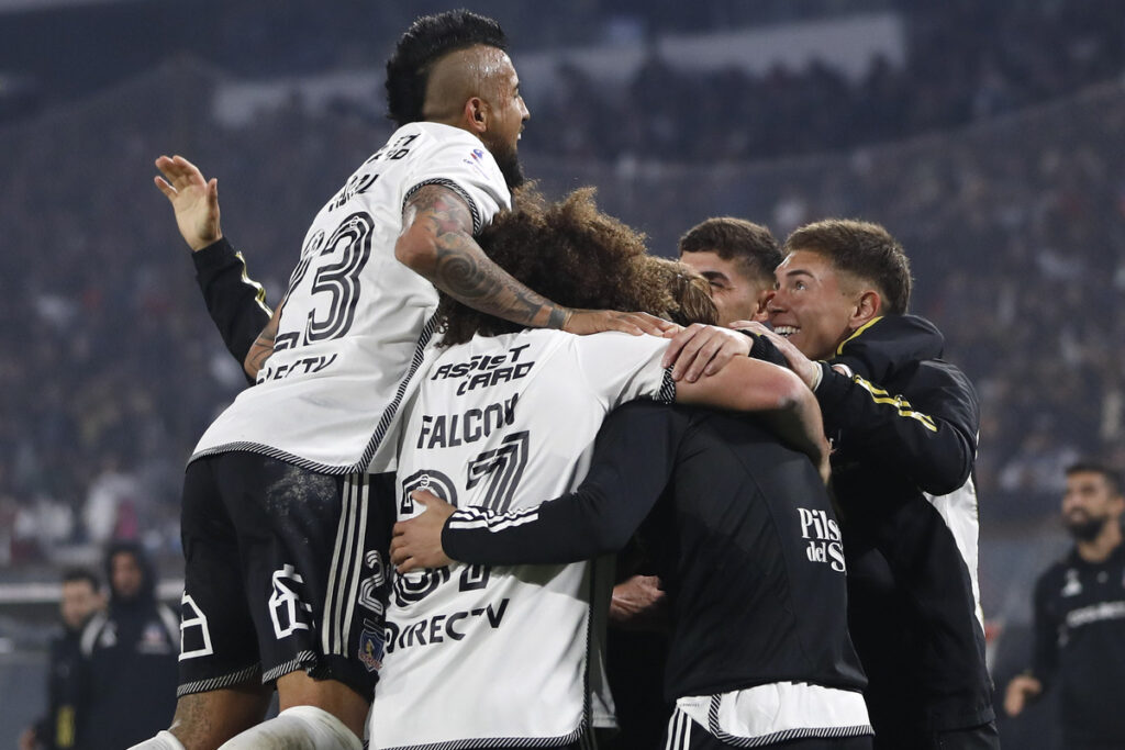 Jugadores de Colo-Colo abrazados celebrando un gol.