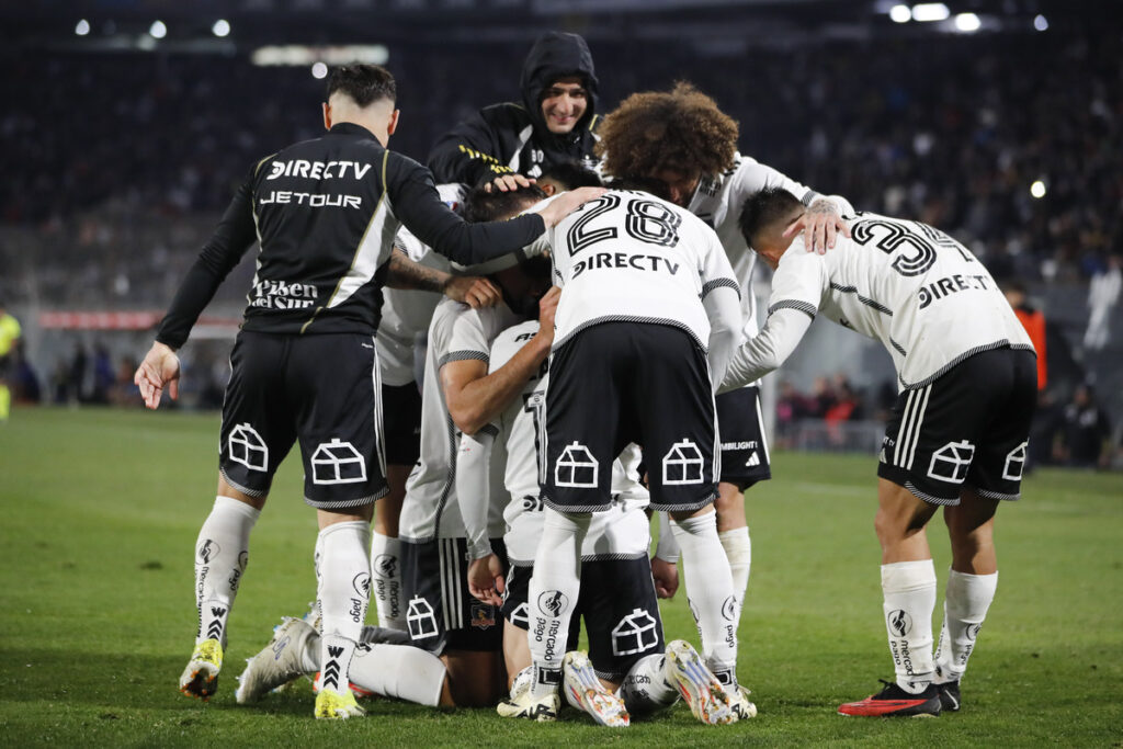 Jugadores de Colo-Colo abrazados celebrando un gol.