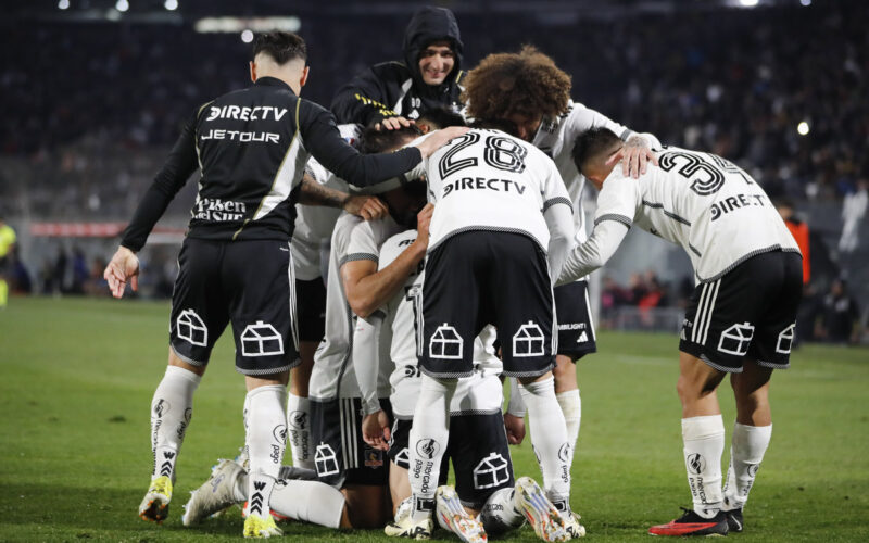 Jugadores de Colo-Colo abrazados celebrando un gol.