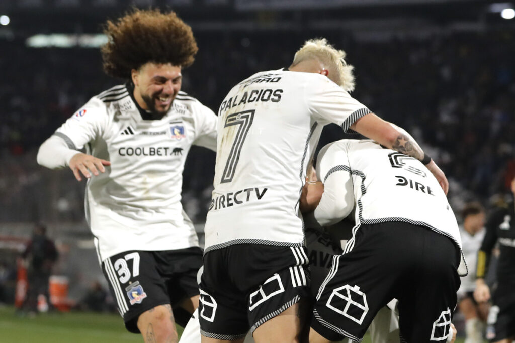 Jugadores de Colo-Colo abrazados celebrando un gol.