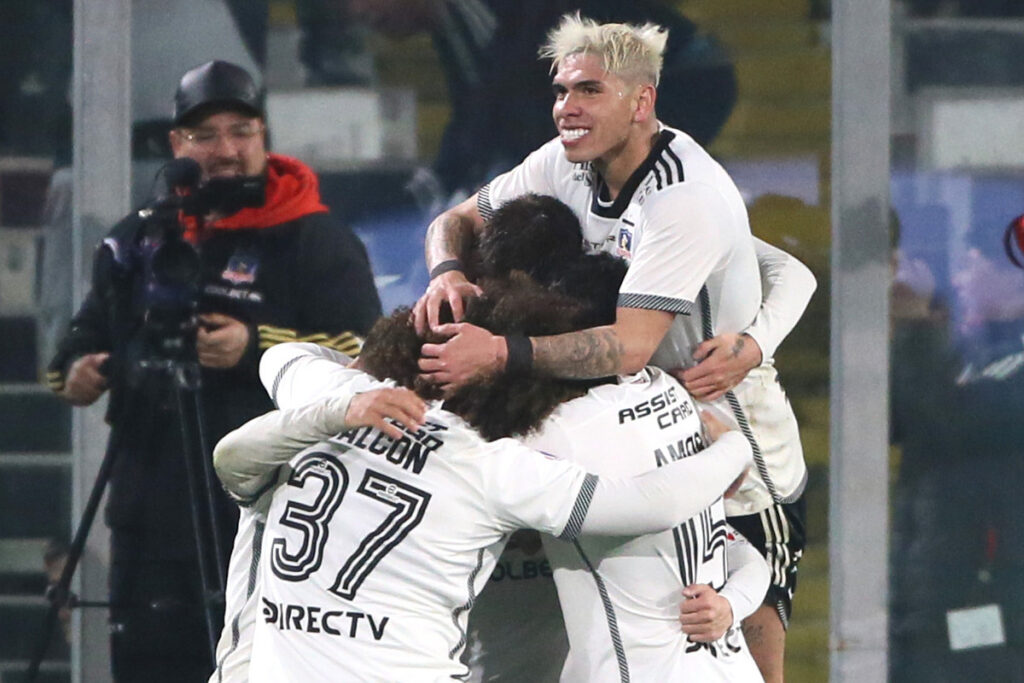 Jugadores de Colo-Colo abrazados celebrando un gol.