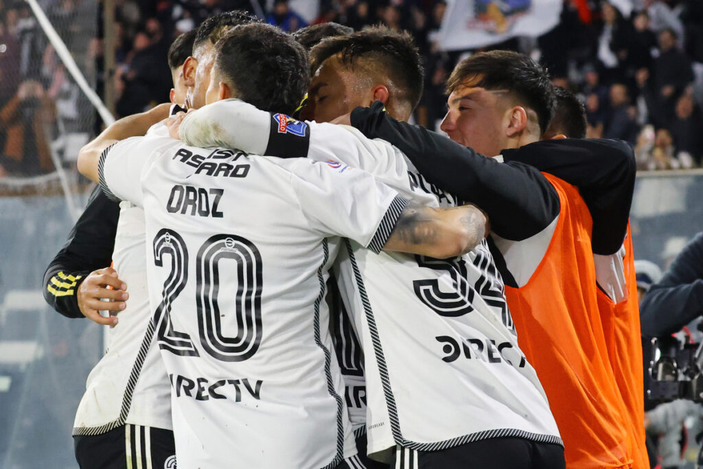 Jugadores de Colo-Colo abrazados celebrando un gol.