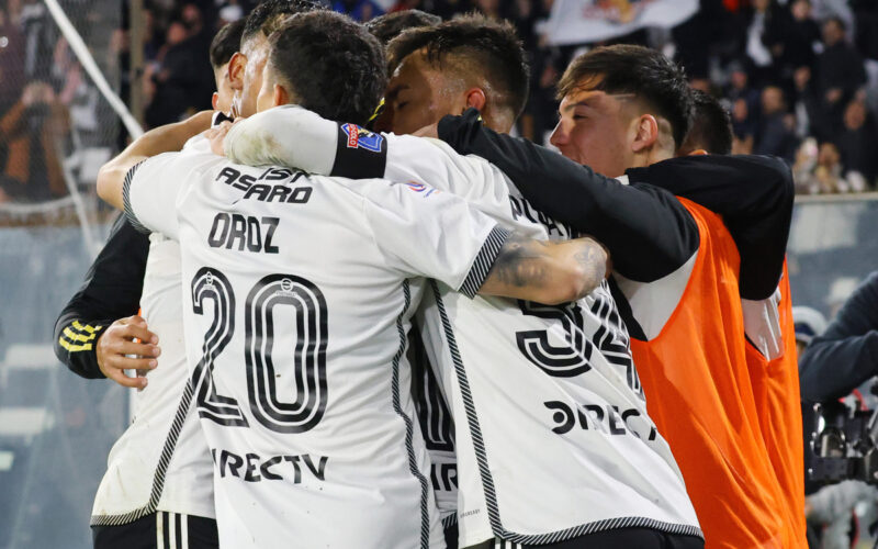 Jugadores de Colo-Colo abrazados celebrando un gol.