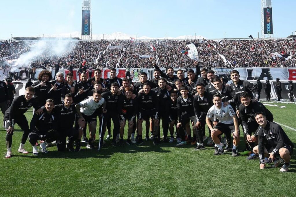 Jugadores de Colo-Colo posando con la hinchada alba de fondo en el sector cordillera.