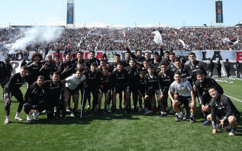 Jugadores de Colo-Colo posando con la hinchada alba de fondo en el sector cordillera.