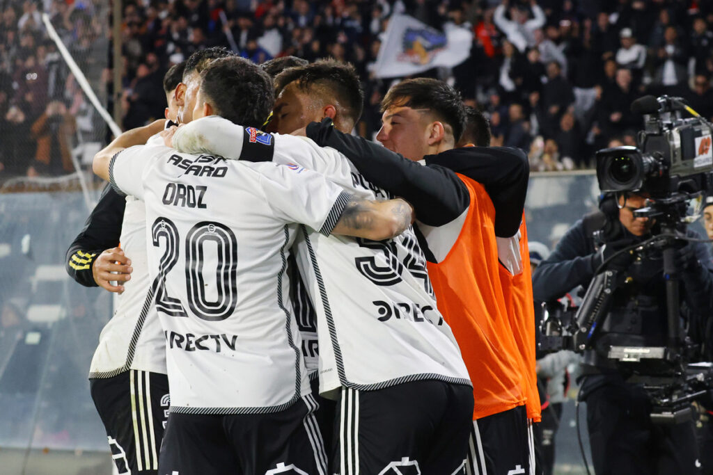 Jugadores de Colo-Colo abrazados celebrando un gol.