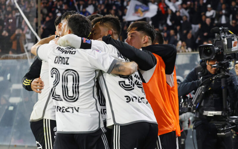 Jugadores de Colo-Colo abrazados celebrando un gol.