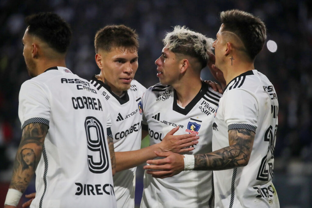 Jugadores de Colo-Colo abrazados celebrando un gol.