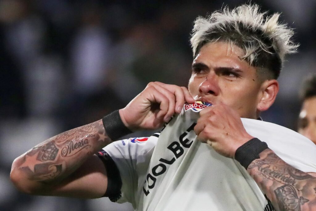 Primer plano a Carlos Palacios celebrando un gol besando el escudo de Colo-Colo.