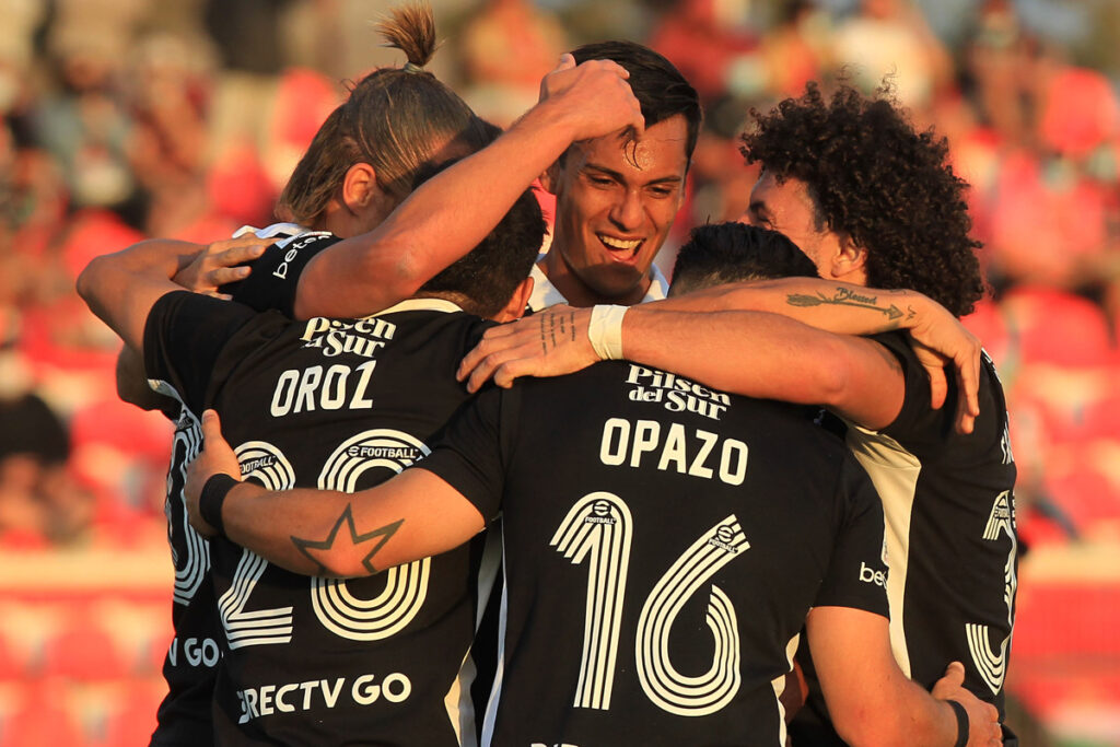 Jugadores de Colo-Colo abrazados celebrando un gol.