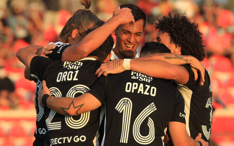 Jugadores de Colo-Colo abrazados celebrando un gol.