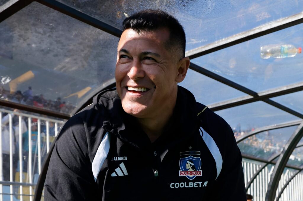 Primer plano a Jorge Almirón sonriendo en el banco de Colo-Colo.