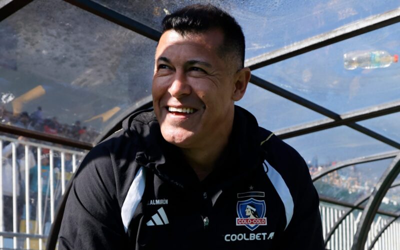 Primer plano a Jorge Almirón sonriendo en el banco de Colo-Colo.