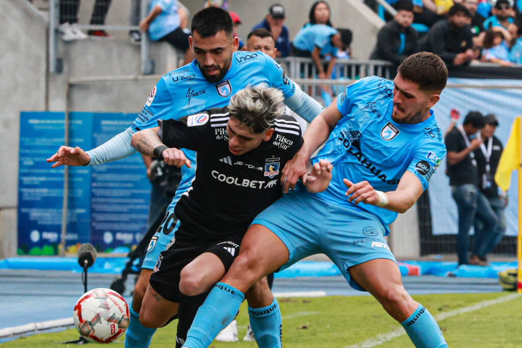 Carlos Palacios jugando por Colo-Colo frente a la marca de dos jugadores de Deportes Iquique.