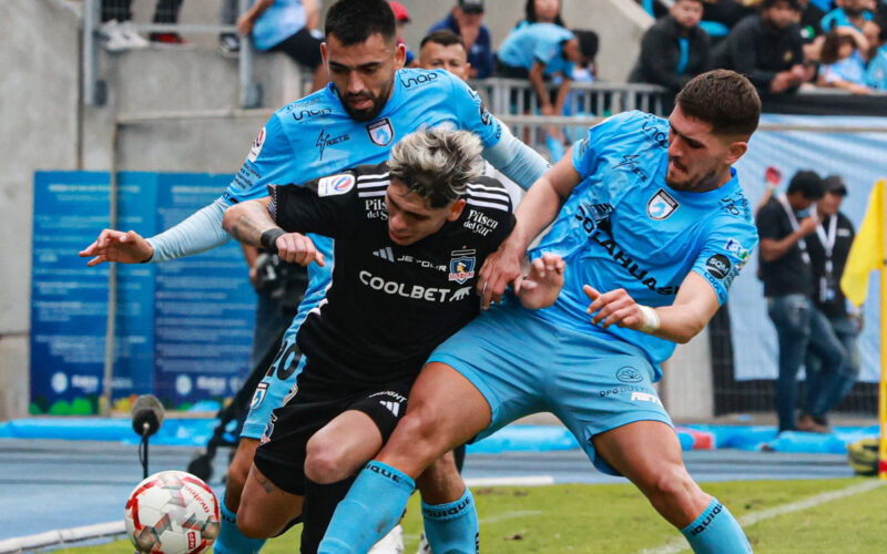 Carlos Palacios jugando por Colo-Colo frente a la marca de dos jugadores de Deportes Iquique.