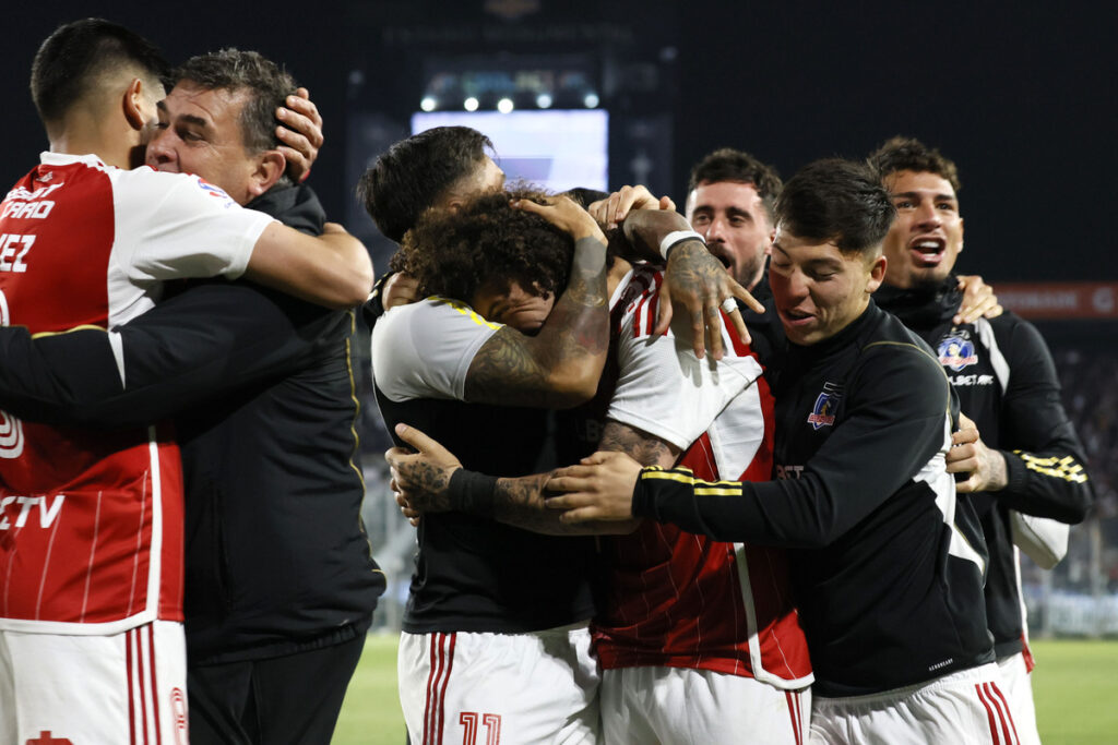 Jugadores de Colo-Colo abrazados celebrando un gol.