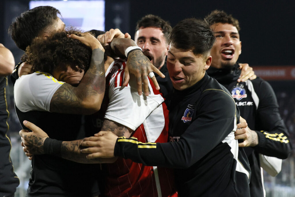 Jugadores de Colo-Colo abrazados celebrando un gol.