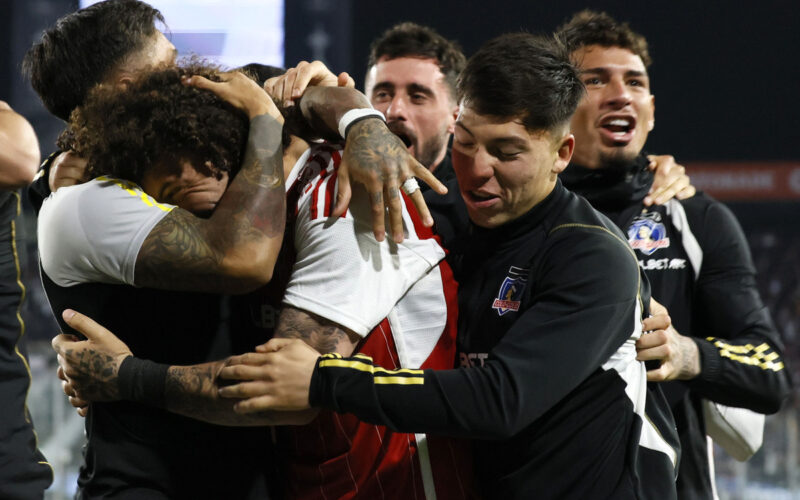 Jugadores de Colo-Colo abrazados celebrando un gol.