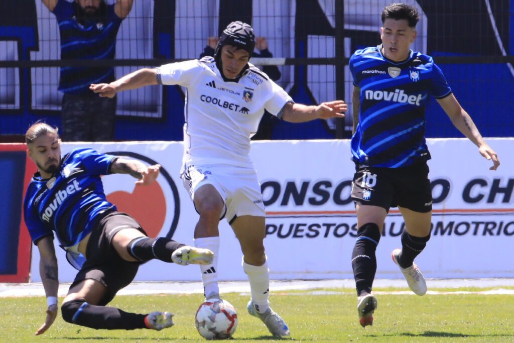 Vicentel Pizarro luchando un balón frente a dos jugadores de Huachipato.